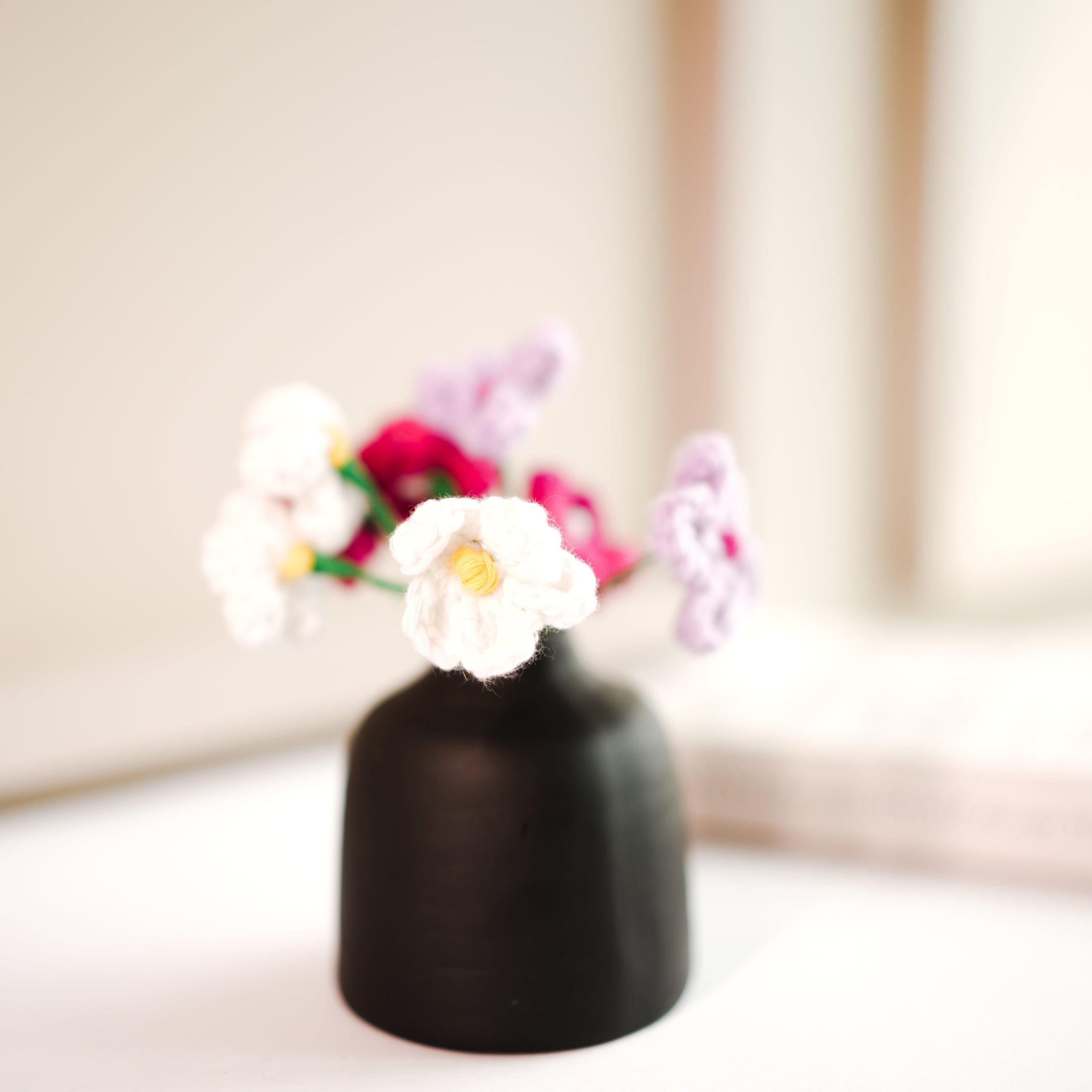 black bud vase with mini crochet daisies