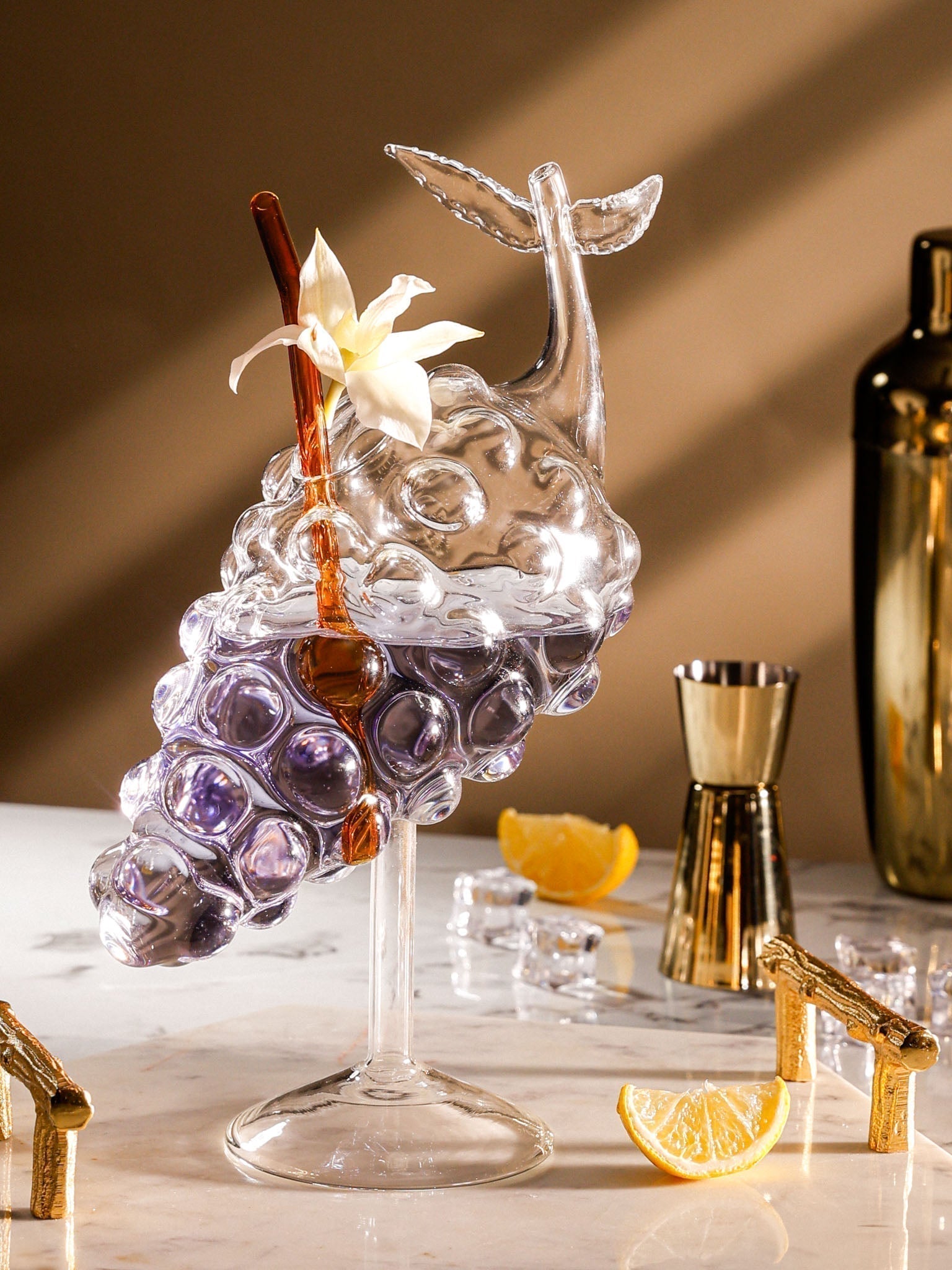 Decorative glass with grapes and a lemon on a marble surface with a brown background