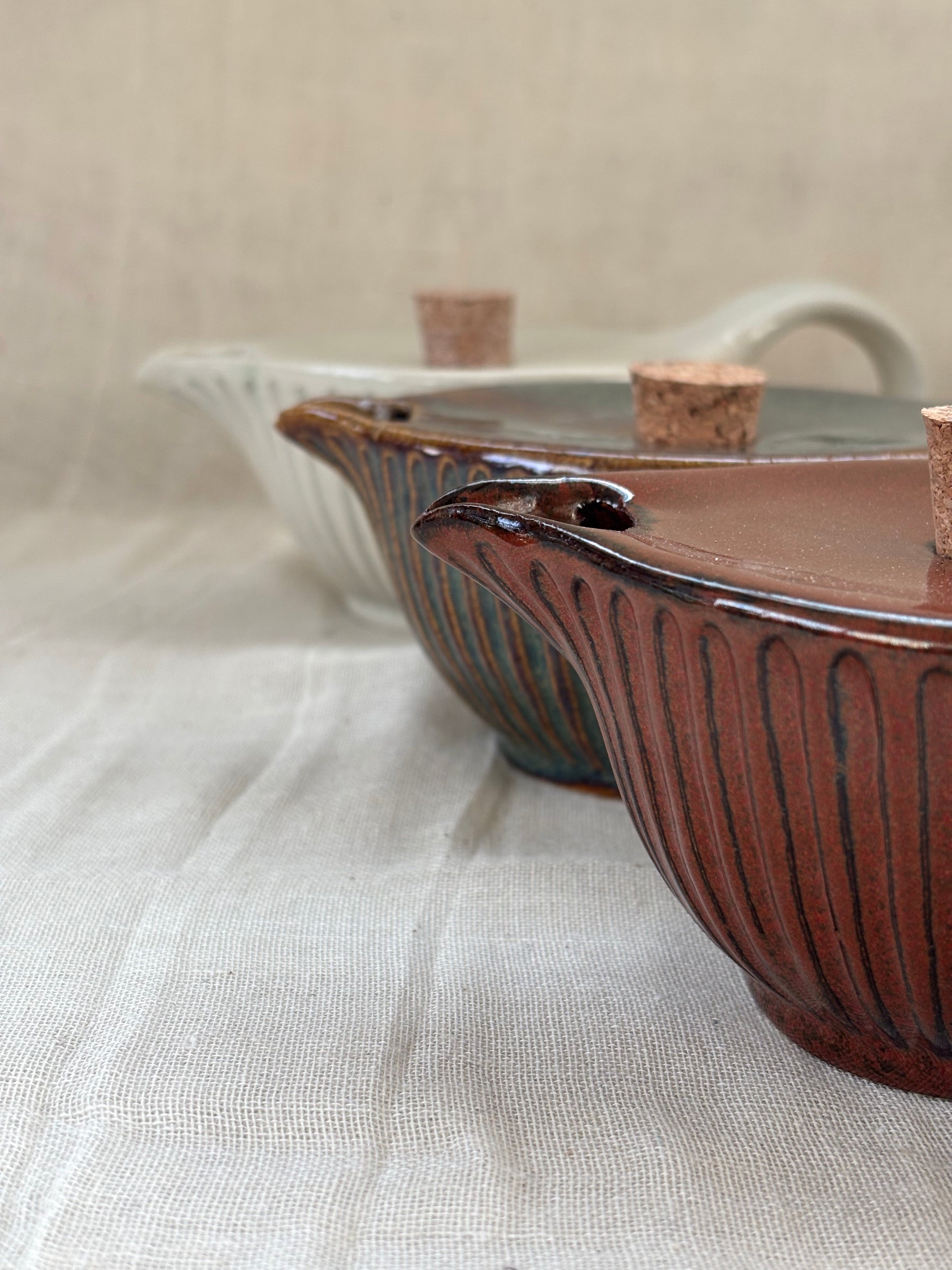 Two ceramic pots with ribbed design on a textured surface