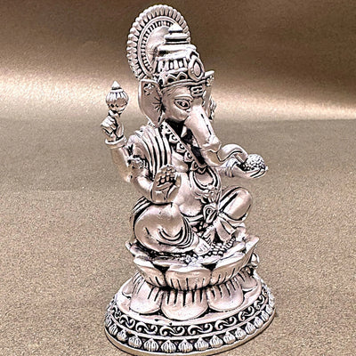 Silver Ganesh statue with intricate detailing on a gold surface, Sabera home decor