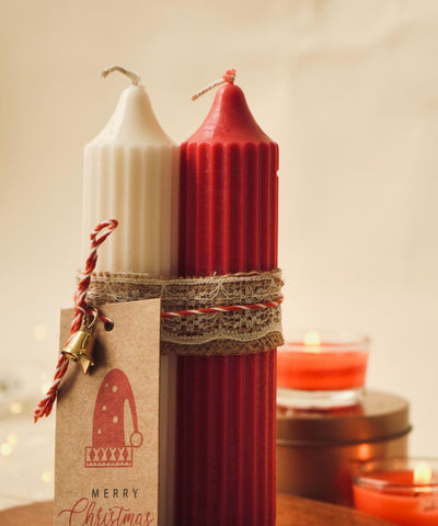 Red and white candles with a Christmas tag on a wooden surface.