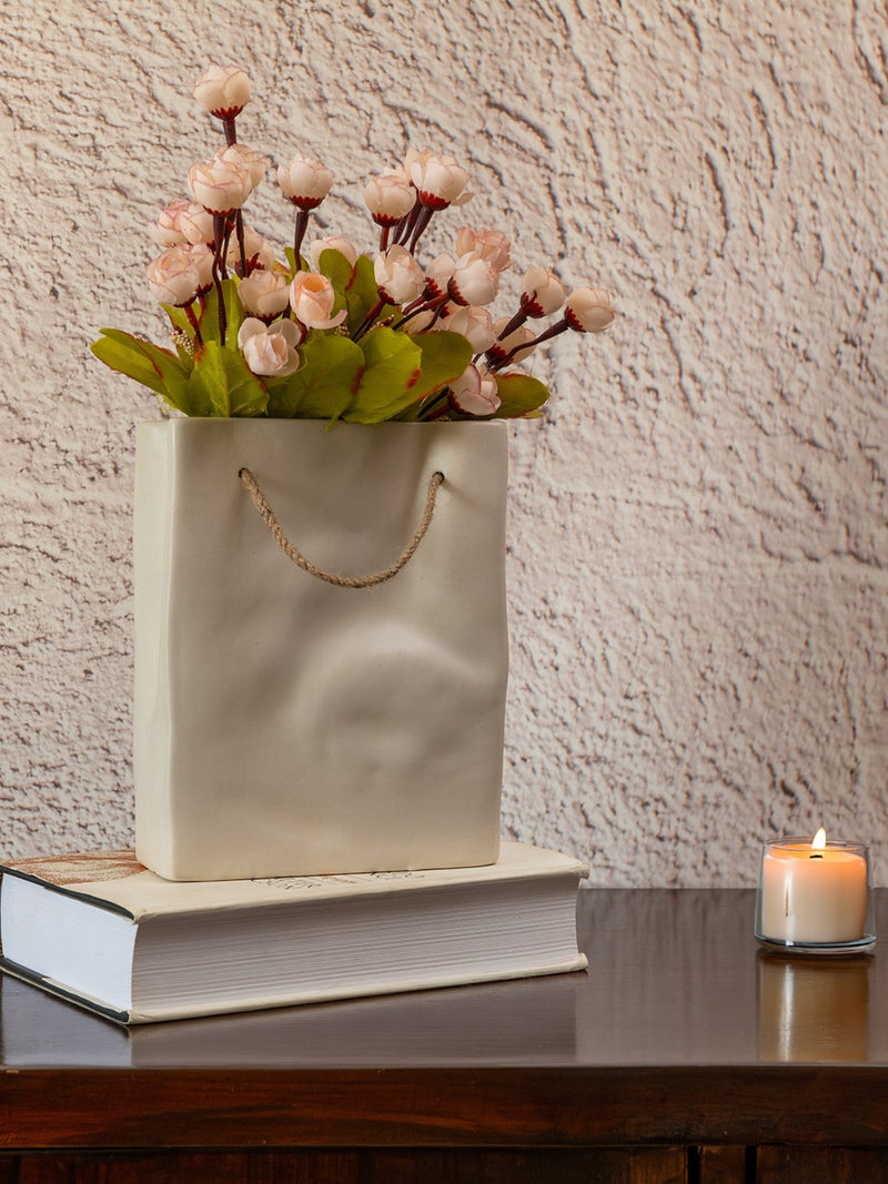White paper bag with pink flowers on a book against a textured wall.