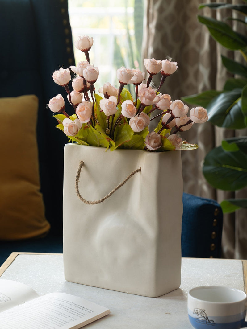 White vase with pink flowers on a table in a home setting