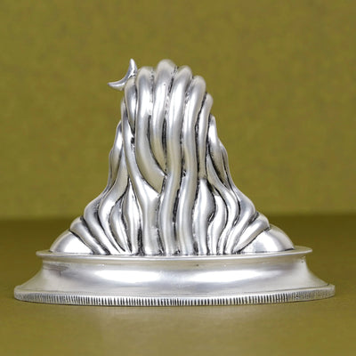 Silver Adi Yogi Shiva idol for car dashboard, detailed back view on olive surface