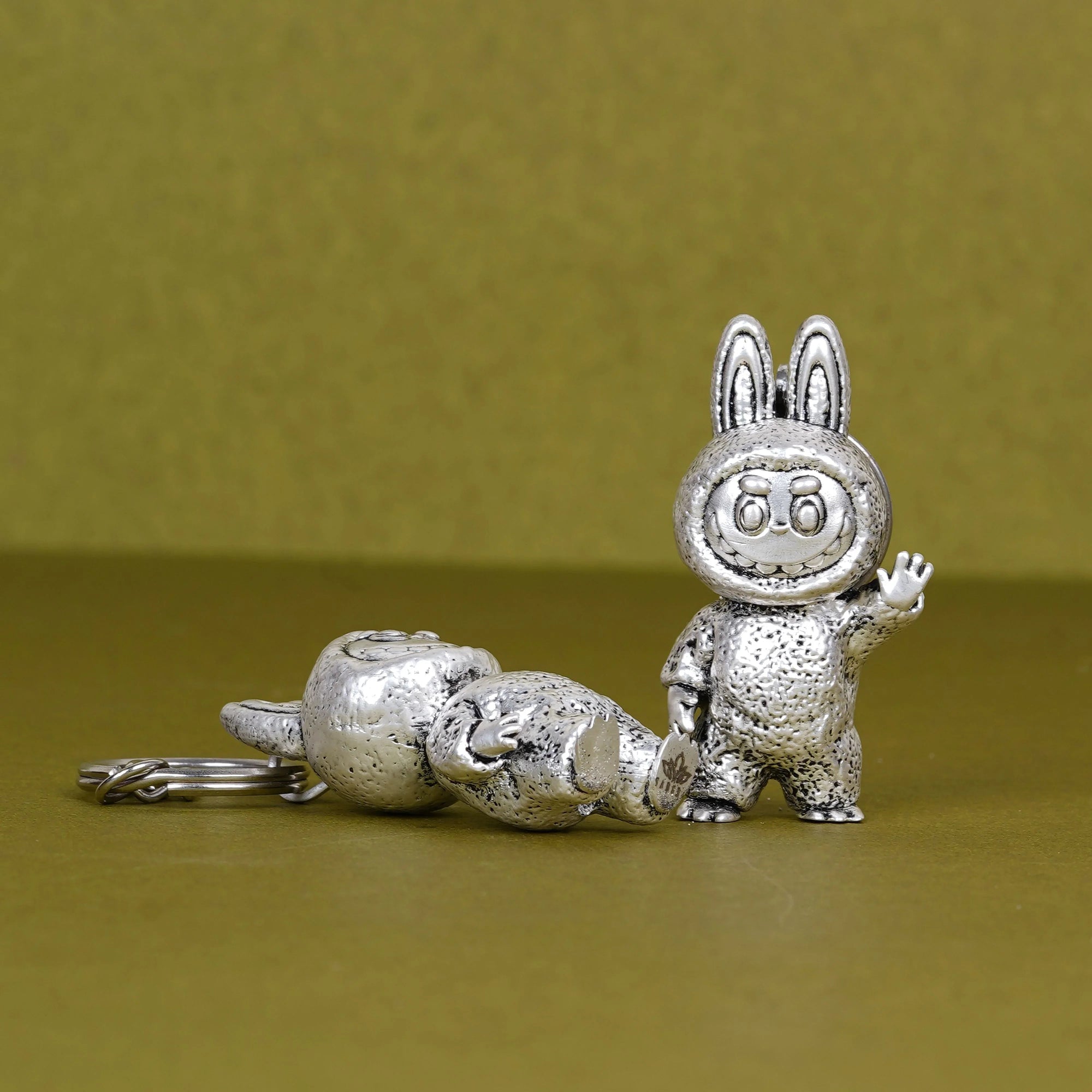 Elegant silver-plated 3D Labubu keychain on olive surface, Sabera product image