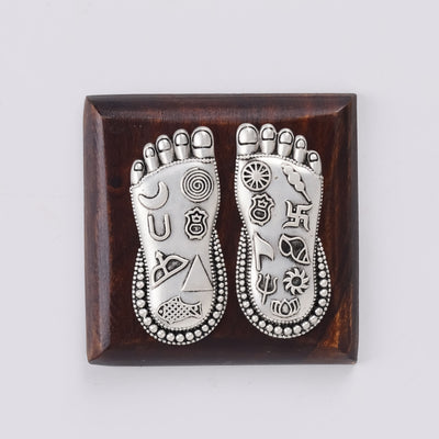 Lakshmi Charan foot silver charm on square wooden base, top view